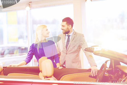 Image of happy couple buying car in auto show or salon