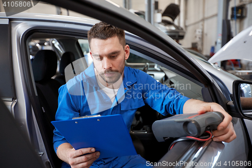 Image of mechanic man with diagnostic scanner at car shop