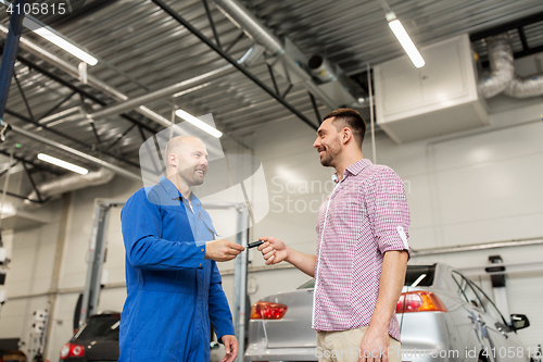 Image of auto mechanic giving key to man at car shop