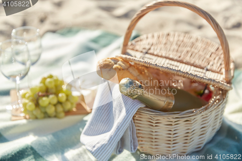 Image of picnic basket with wine glasses and food on beach