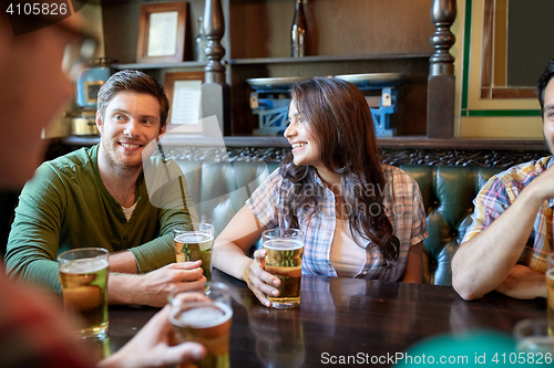 Image of happy friends drinking beer at bar or pub