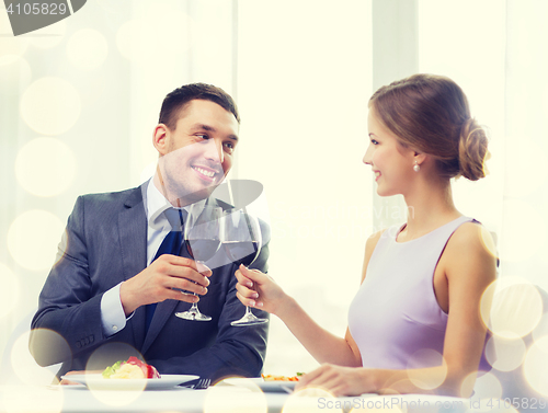 Image of couple with main course and red wine at restaurant