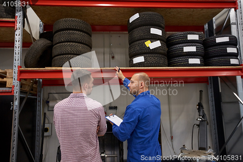 Image of auto mechanic and man with tires at car shop