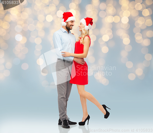 Image of happy couple in santa hats hugging