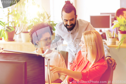 Image of happy creative team with computer in office