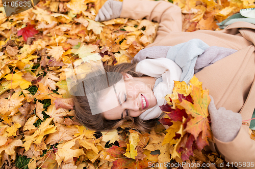 Image of beautiful happy woman lying on autumn leaves