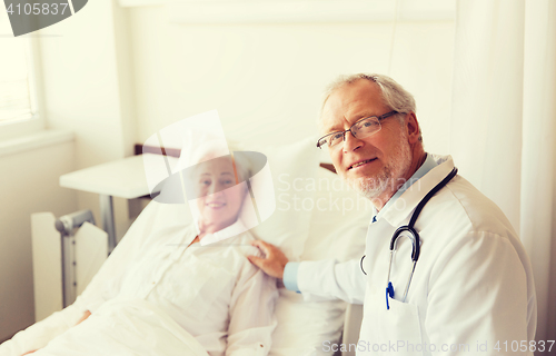 Image of doctor visiting senior woman at hospital ward