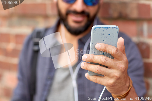 Image of man with earphones and smartphone on street