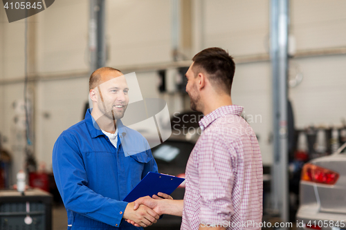 Image of auto mechanic and man shaking hands at car shop