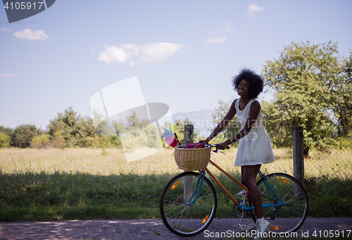 Image of pretty young african american woman riding a bike in forest