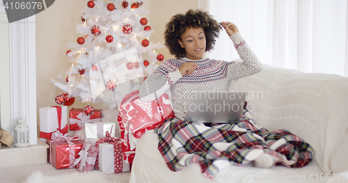 Image of Young woman relaxing in front of a Christmas tree