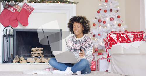 Image of Young woman doing Christmas shopping online