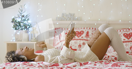 Image of Trendy young woman listening to Christmas music