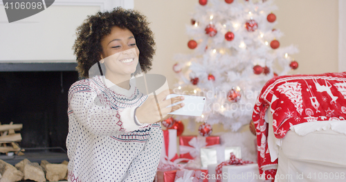 Image of Happy young woman posing for a Christmas selfie