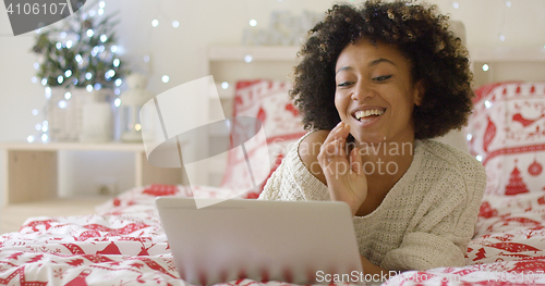 Image of Beautiful woman in bed laughing at computer