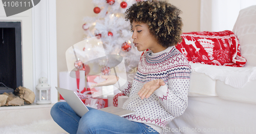 Image of Cute young woman having a video chat at Christmas