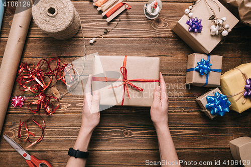 Image of Crop hands holding wrapped present on table