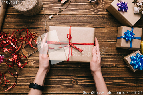 Image of Crop hands holding wrapped present on table