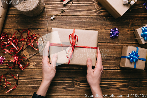 Image of Crop hands holding wrapped present on table