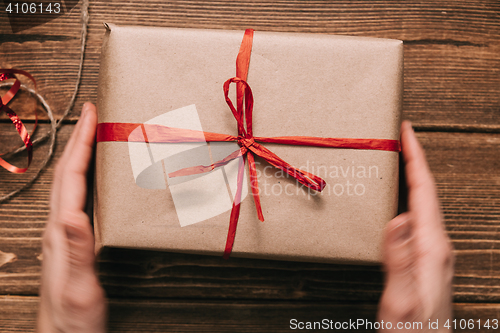 Image of Crop hands holding wrapped present on table