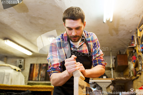 Image of carpenter working with plane and wood at workshop