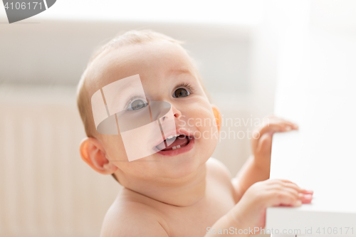 Image of happy little baby boy or girl at home looking up