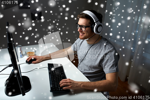 Image of man in headset playing computer video game at home