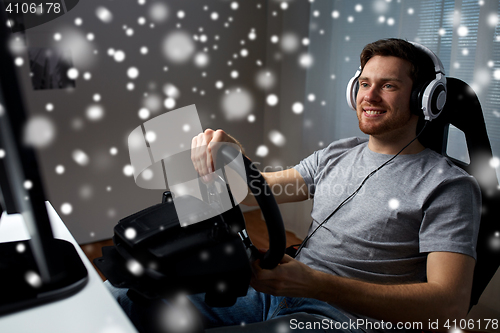 Image of man playing car racing video game at home