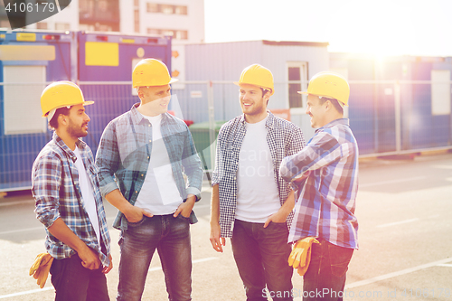 Image of group of smiling builders in hardhats outdoors