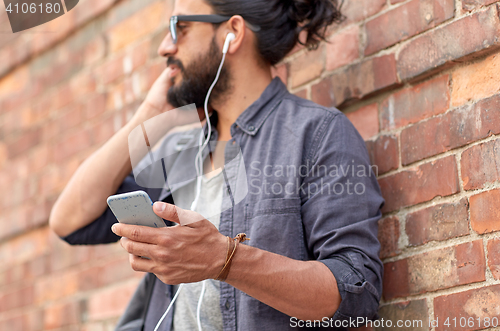 Image of man with earphones and smartphone on street