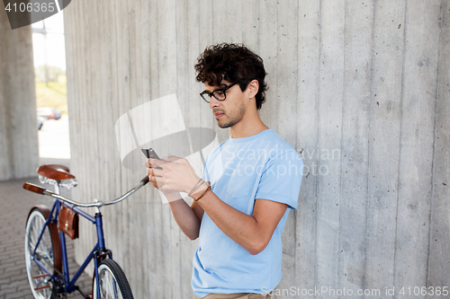 Image of man with smartphone and fixed gear bike on street