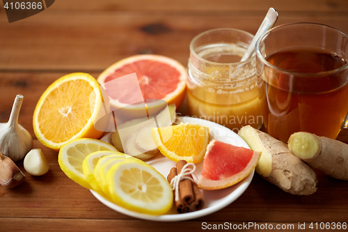 Image of ginger tea with honey, citrus and garlic on wood