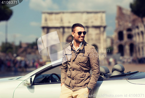 Image of happy man driving cabriolet car over city of rome