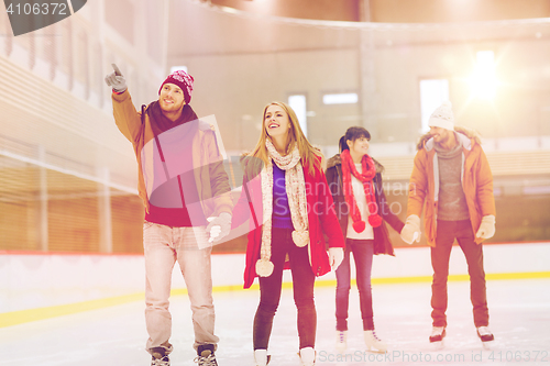 Image of happy friends pointing finger on skating rink