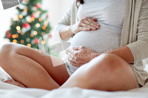 Image of close up of pregnant woman sitting in bed at home