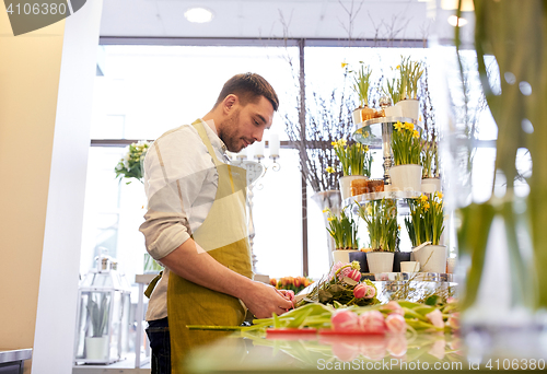 Image of smiling florist man making bunch at flower shop