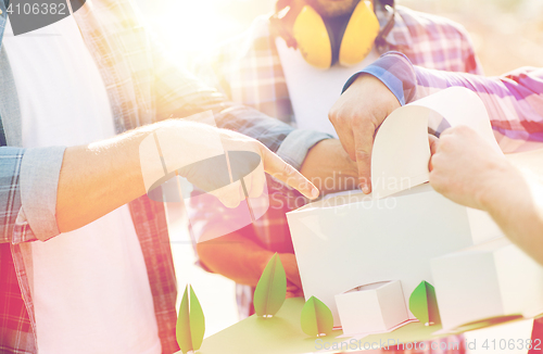 Image of close up of builders with paper house model