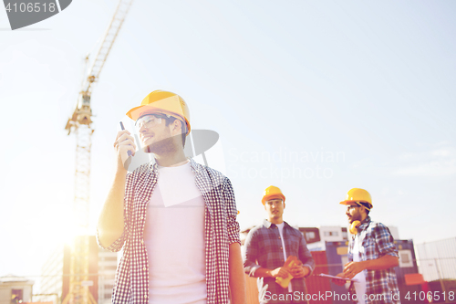 Image of group of smiling builders in hardhats with radio