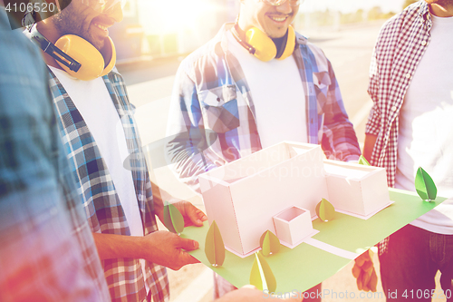 Image of close up of builders with paper house model