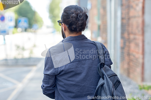 Image of man with backpack walking along city street