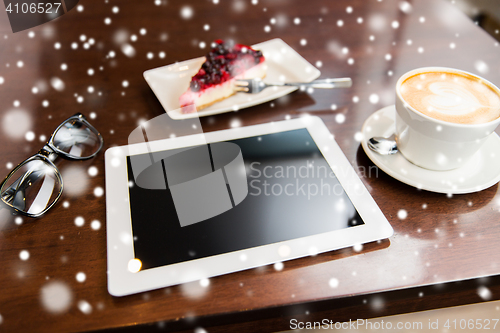 Image of close up of tablet pc, coffee cup and cake