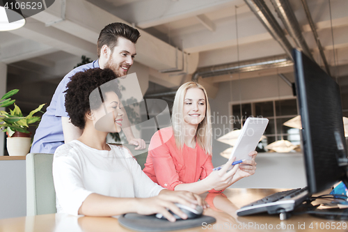 Image of happy creative team with computer in office