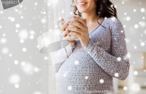 Image of close up of pregnant woman with tea cup at window