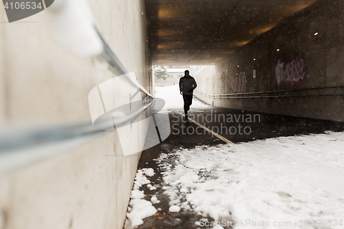 Image of man running along subway tunnel in winter