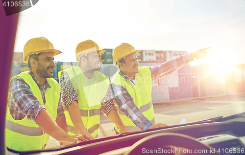 Image of close up of builders with blueprint on car hood