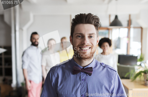 Image of happy young man over creative team in office