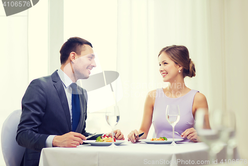 Image of smiling couple eating main course at restaurant