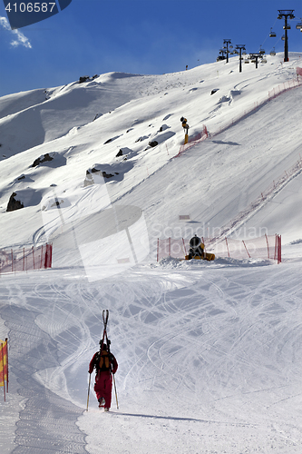 Image of Skier ascend on snow ski slope at sun evening