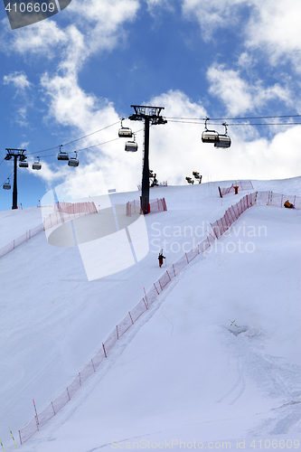 Image of Skier ascend on snow ski slope and ski-lift at evening