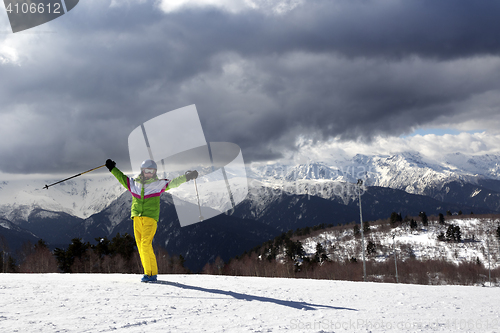 Image of Happy young skier with ski poles in sun mountains and cloudy gra